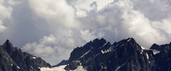 Panoramic view on high mountains with snow and glacier in clouds before rain