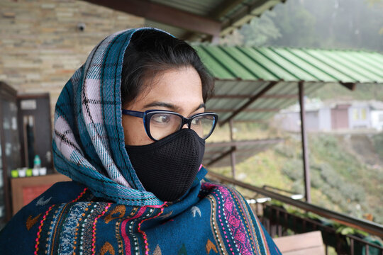 Indian woman wearing a sarong, face mask, and eyewear on a blurry background