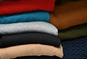 gestapelte gefaltete Pullover in bunten Farben im Kleiderschrank