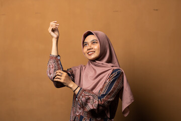 Fashion portrait of young beautiful asian muslim woman with wearing hijab isolated on gold background. 