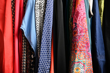 Hängende bunte Kleider Blusen Hemden senkrecht mit Mustern im Schrank