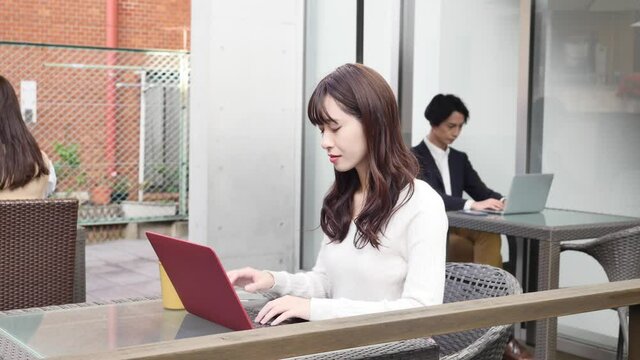 カフェテラスでパソコンを使う女性