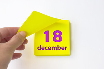 December 18th. Day 18 of month, Calendar date. Hand rips off the yellow sheet of the calendar. Winter month, day of the year concept.