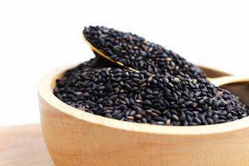 Black sesame seeds in wooden bowl.
