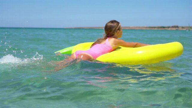 Adorable girl on inflatable air mattress in the sea