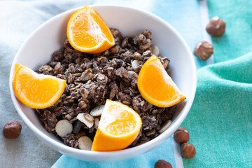 Crunchy chocolate muesli and  tangerine slices  on green blau beige organic cotton table cloth . Favourite breakfast. Sweet breakfast. Sweet moment. Sweet break.