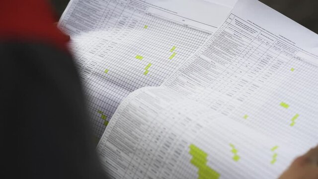 Big list with construction schedule in hand of engineer. standing outdoors. Close up shot