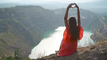 Little girl near the lake at the day time with amazing nature on background