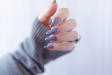 Womans hands with long nails with violet purple nail polish