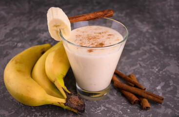 Delicious banana smoothie with cinnamon on a gray background.