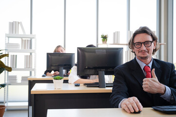 Obraz premium Portrait of businessman wearing suit thumb up and smiling with office at the background.