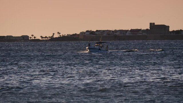 Fishing boat on sea water at morning. Seascape. Tabarca island on horizon.