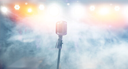 Close-up old retro vintage microphone on glare smoke tinted color background