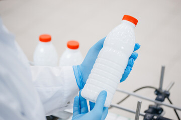Man worker operator inspecting milk bottles production line dairy factory industry, automatic...