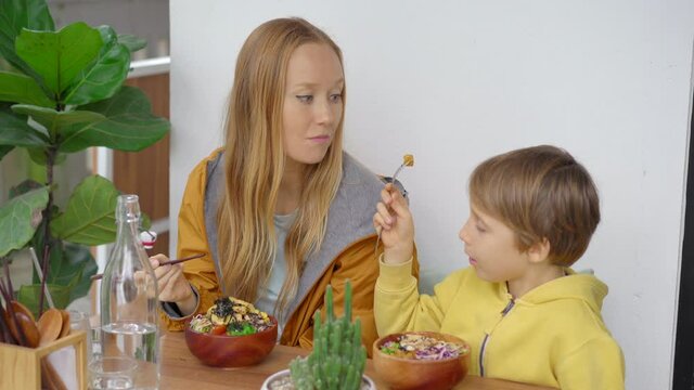 A young woman and her son have a dinner in a beautiful cafe where poke bowls are served. Fast and healthy. Trendy food concept