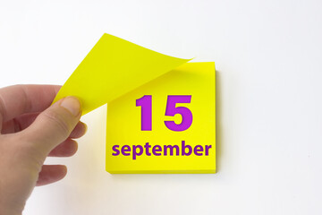 September 15th. Day 15 of month, Calendar date. Hand rips off the yellow sheet of the calendar. Autumn month, day of the year concept.