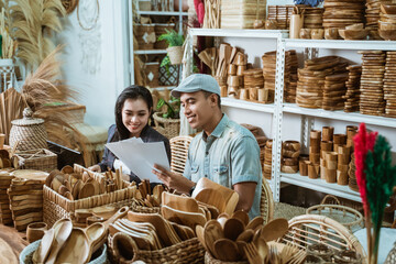 a craftsman gives a paper craft item sketch to a businesswoman while in a handicraft workshop