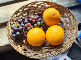 Orange and grapes in the fruit basket. Selective focus.