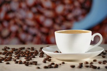 A white cappuccino Cup on the marble table. Coffee beans on the table, blurred background. The foam on the cappuccino is very close