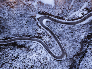 Road with curves and hairpin bends in a snowy forest