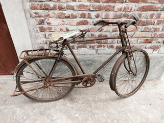 Rusty vintage old fashioned bicycle leaning against a brick wall.