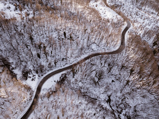 Road with curves and hairpin bends in a snowy forest