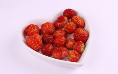 Red strawberries in a plate in the shape of a heart 