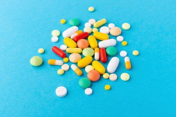 Assorted pharmaceutical medicine pills, tablets and capsules over blue background, with copy space. Top view. Close up.