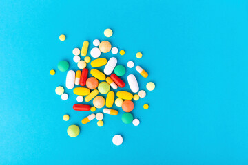 Assorted pharmaceutical medicine pills, tablets and capsules over blue background, with copy space. Flat lay, top view. Close up.