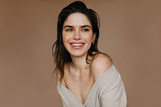 Cheerful caucasian girl smiling on brown background. Studio portrait of charming female model with black hair.
