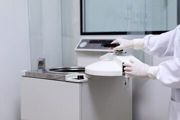Unidentified operator's hand is open the lid of autoclave to prepare loading the media for sterilization in the microbiological laboratory room of pharmaceutical industries.