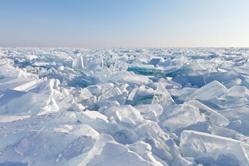 Fototapeta premium Endless hummock field on the frozen Lake Baikal. Piles of snow-covered debris of blue ice on a sunny frosty day. Cold natural background. Unusual winter landscape