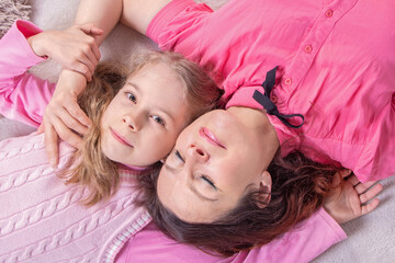 top view little girl and young caucasian mom lying down and enjoy each other
