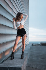 Fashion photoshoot with a brunette girl in the city at blue hour next to a gray building