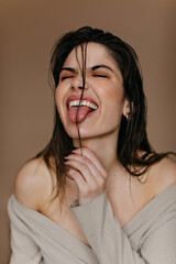 Enthusiastic lady making funny faces. European girl fooling around on brown background.