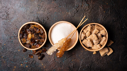 Bowls of brown cane lump and granulated white sugar with cristal sugar stick