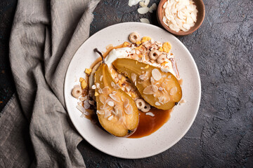 Tasty dessert of baked pears with caramel sauce, cheese cream and almond flakes