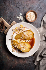 Tasty dessert of baked pears with caramel sauce, cheese cream and almond flakes