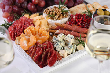 Delicacy assorted appetizer platter of salami and cheese, grissini wrapped in Parma ham, olives and citrus fruits. An original antipasto serving for a party.