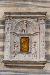 Close-up on gate decorated with catholic symbols carved on marble wall in a church in Rome