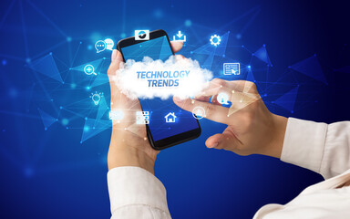 Female hand holding smartphone with TECHNOLOGY TRENDS inscription, cloud technology concept