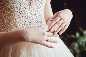 hands of the bride with a stylish manicure on the bodice of a luxurious wedding dress, embroidered with beads and crystals