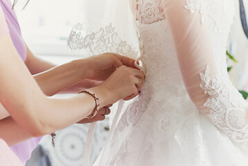 bridesmaids lace up the corset of the wedding dress. preparation for the ceremony, the morning of...