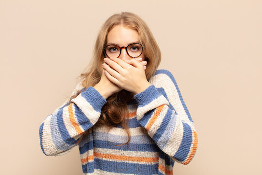 blonde woman covering mouth with hands with a shocked, surprised expression, keeping a secret or saying oops