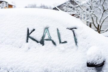Ein schneebedecktes Auto mit dem Text Kalt auf einem Seitenfenster. Winter, Kälte, Sturm.