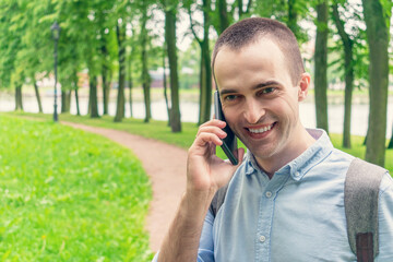 Attractive happy young man talk on phone and walk on street, portrait, close up