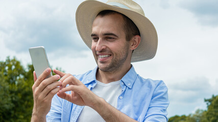 Joyful cowboy uses phone, happy man in hat smiling and reads SMS, portrait,16:9, toned