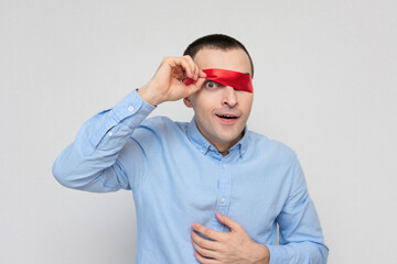 Playful funny man removes blindfold, portrait, white background, copy space