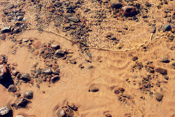 Background of transparent sea water and bottom with rocks, close-up, top view