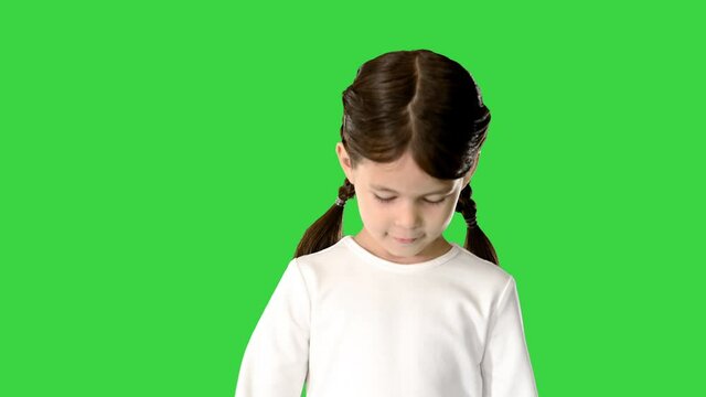 Shy Little Girl With Pig Tails Dressed In White Long Sleeve Top Walking And Looking Down At Her Feet And Camera On A Green Screen, Chroma Key.